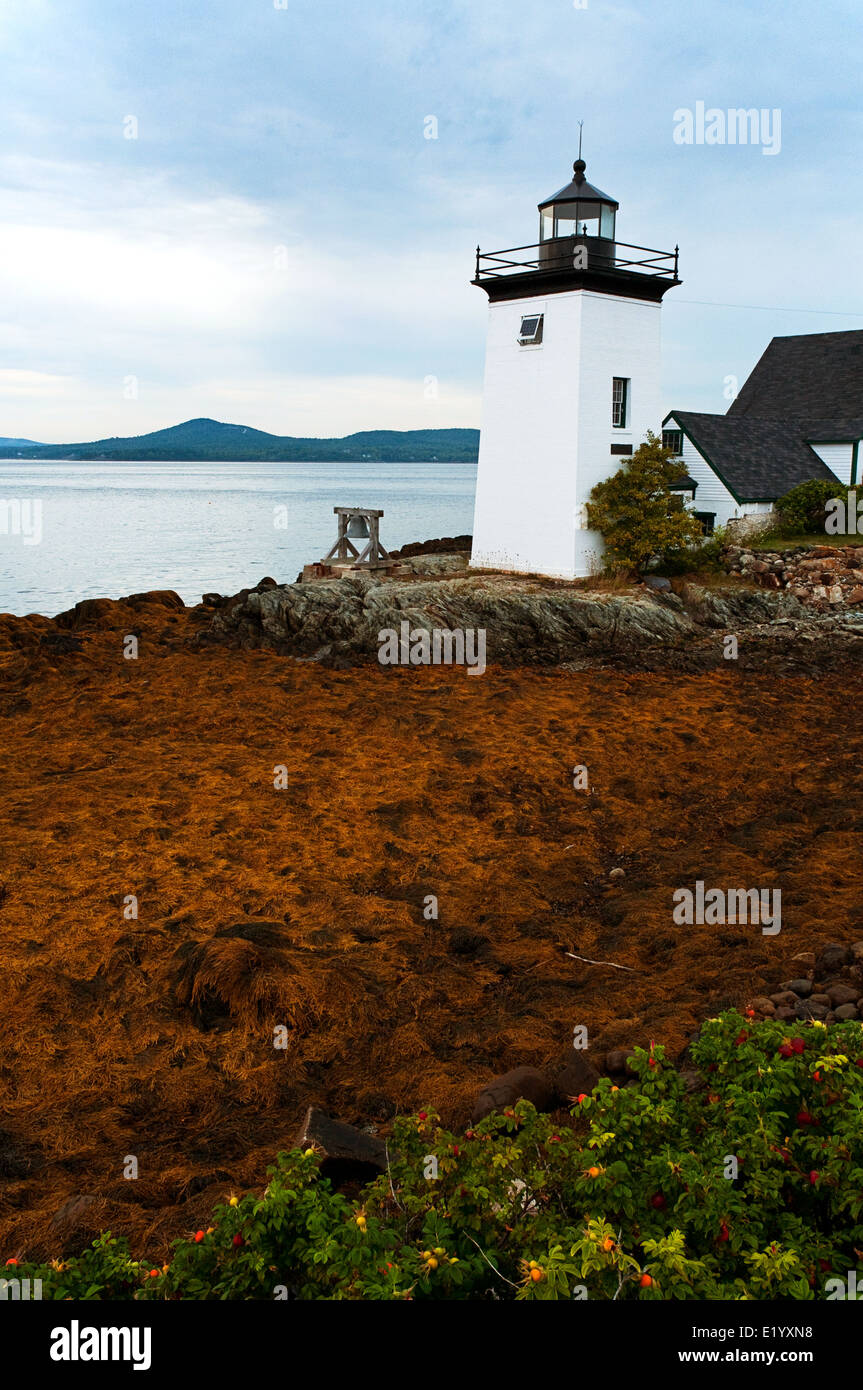 Sun breaks through clouds by Grindle Point lighthouse at low tide on Islesboro Island, in Maine. Stock Photo