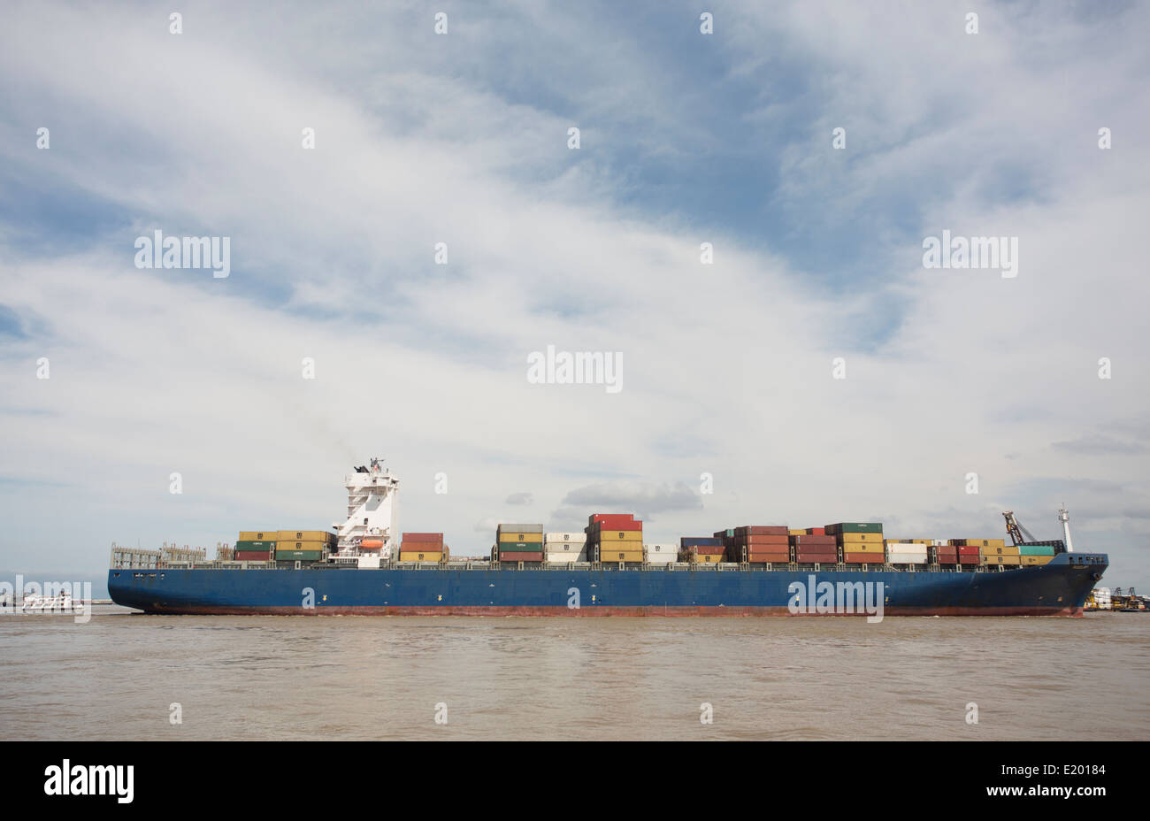 A wide angle view of a cargo ship against a bright, blue and white sky. Stock Photo