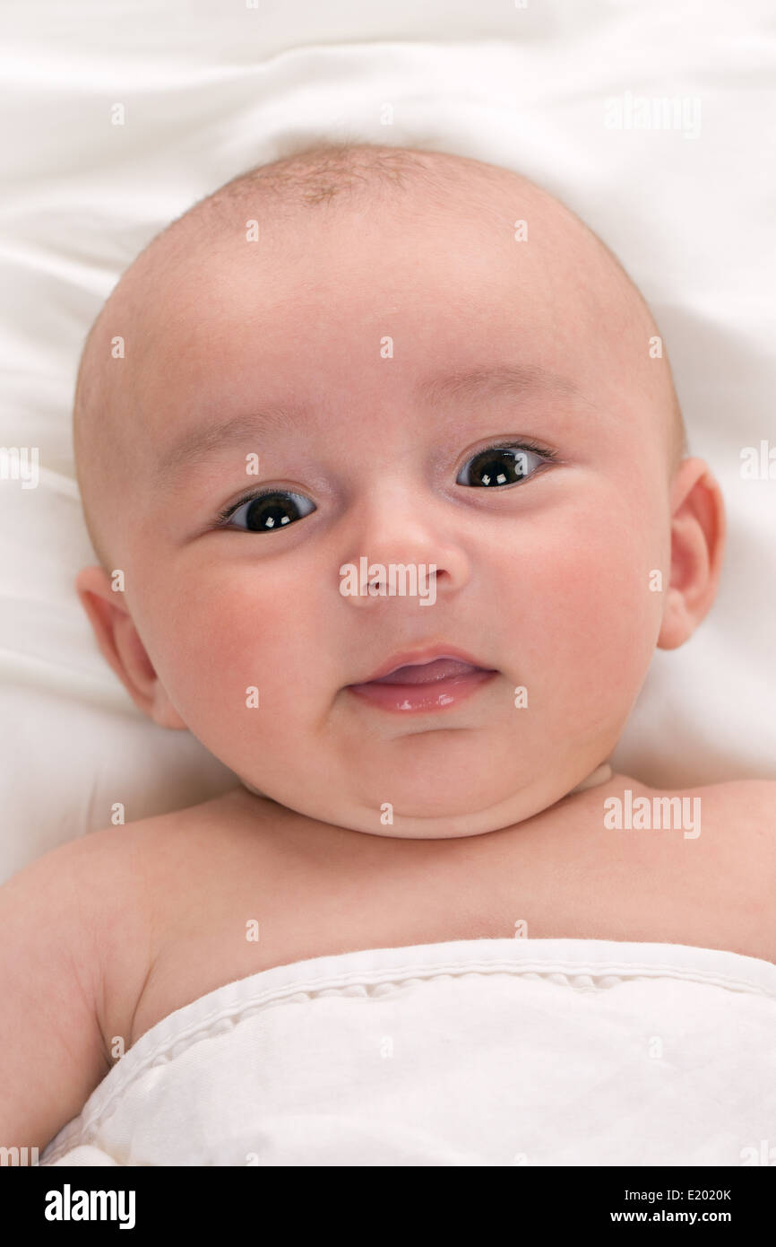 Portrait of a happy baby lying in bed Stock Photo Alamy