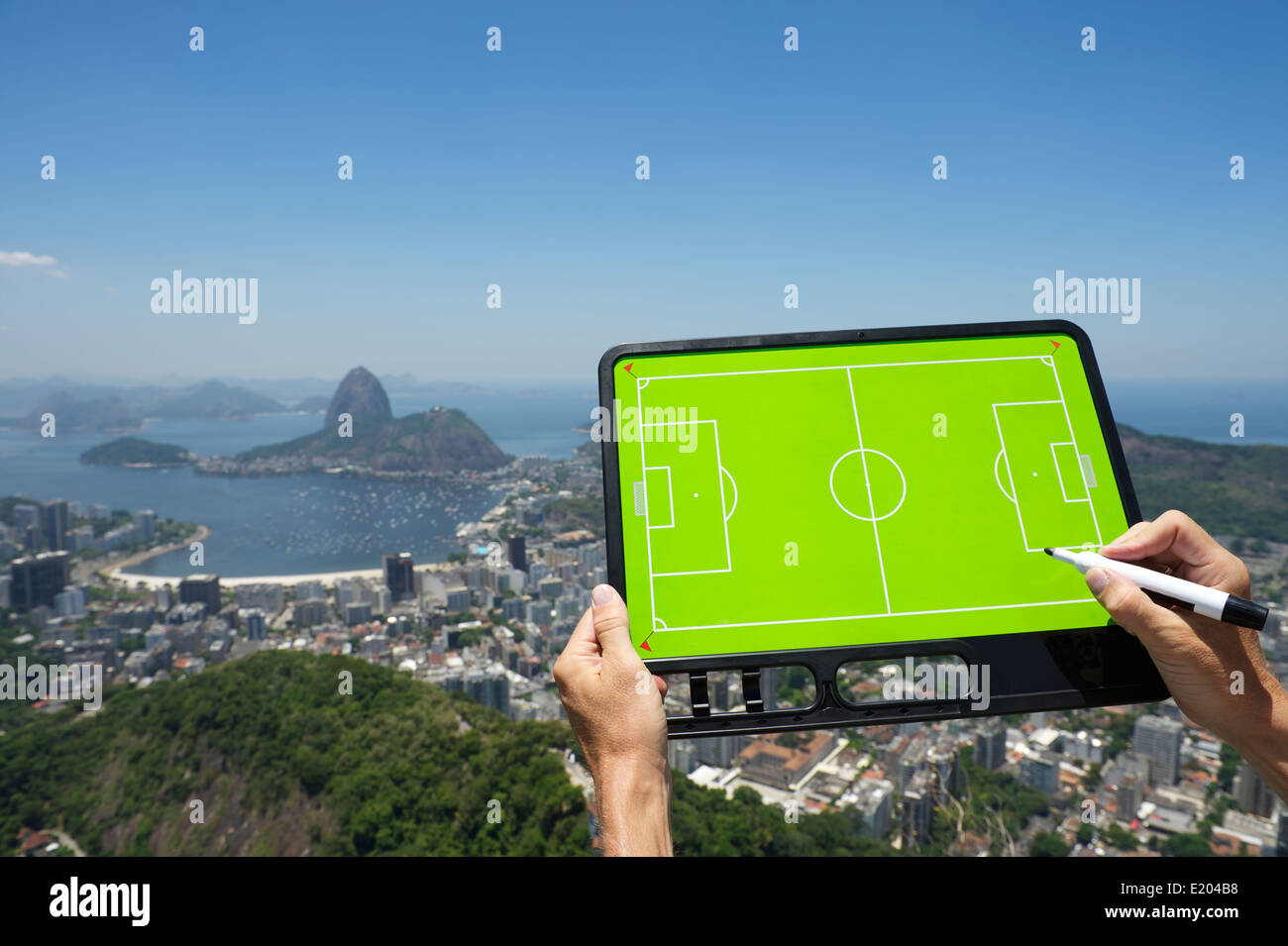 Hands holding soccer football tactics board and pen above skyline overlook of Rio de Janeiro Brazil Stock Photo