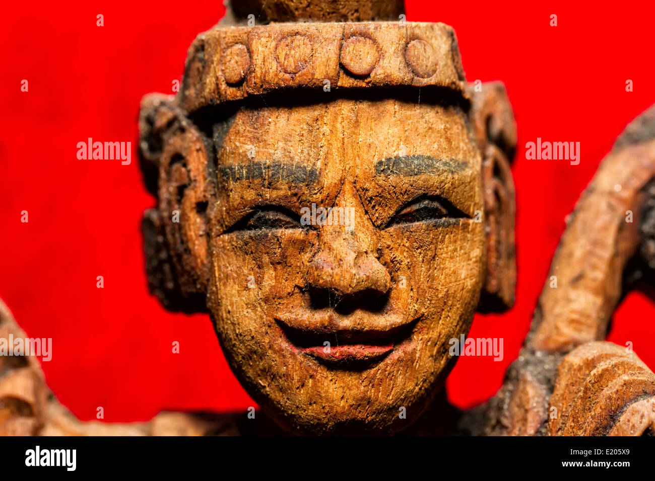 Carved wooden figure Shwe In Bin Kyaung Pagoda with a bright red pillar in background Mandalay Myanmar Burma Stock Photo