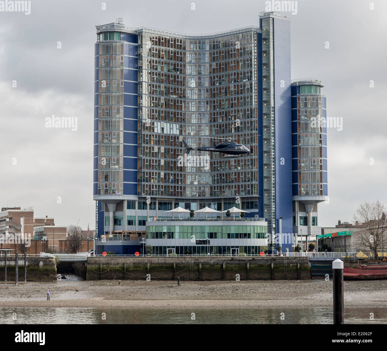 A helicopter leaving Battersea Heliport, London, and flying in front of Falcon Wharf on a cloudy day Stock Photo