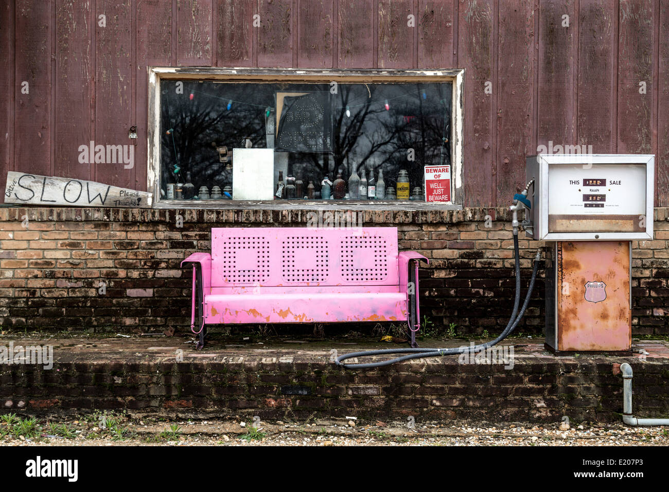 Old gas station with pump, in front a pink metal sofa, Clarksdale, Mississippi, United States Stock Photo