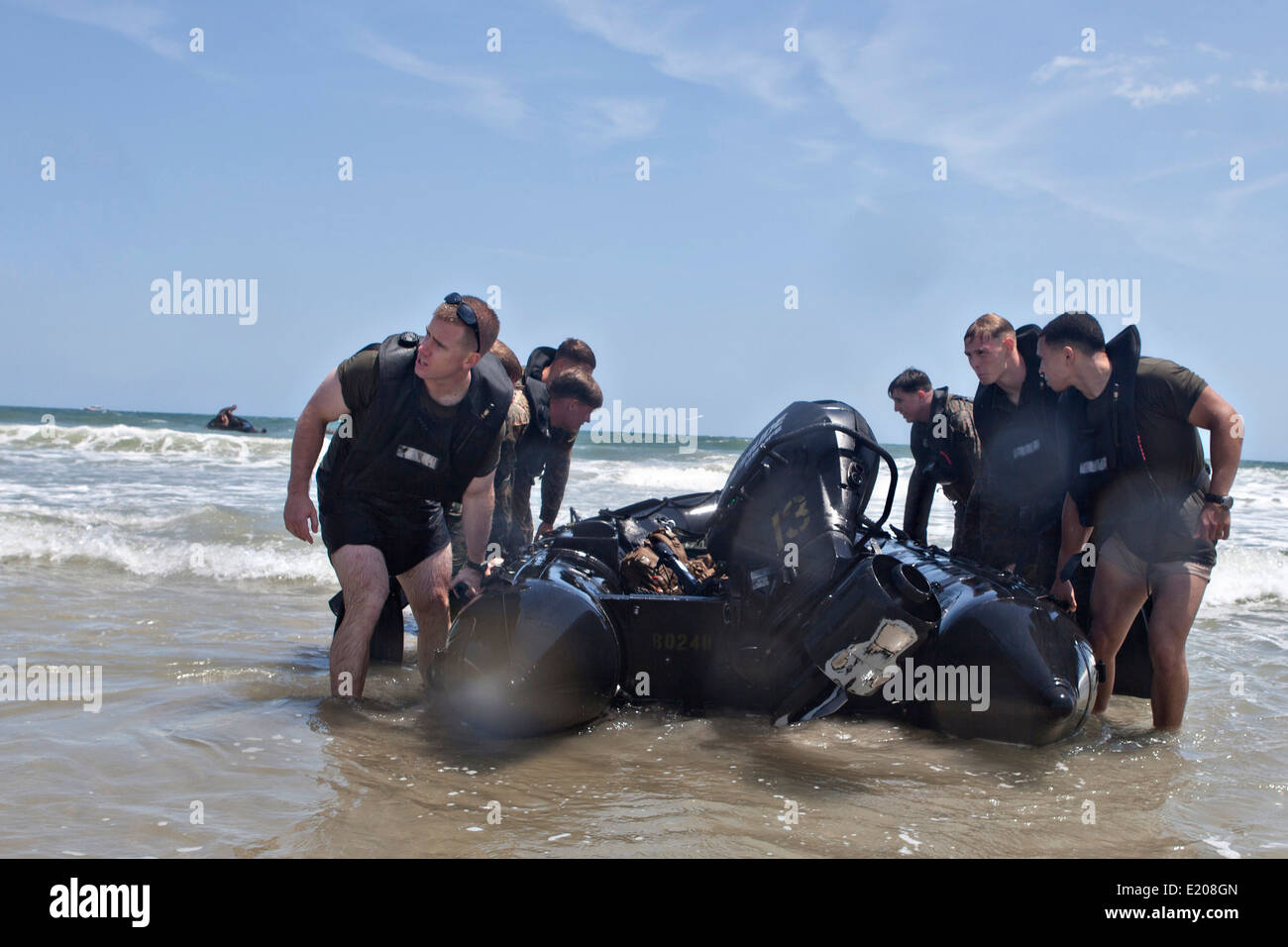 US Marines reconnaissance commandos maneuver an F470 combat rubber raiding craft onto the beach after conducting a hard duck insertion at Onslow Beach June 4, 2014 in Camp Lejeune, N.C. A hard duck insertion involves dropping a fully inflated rubber boat with Marines into the water from a helicopter. Stock Photo