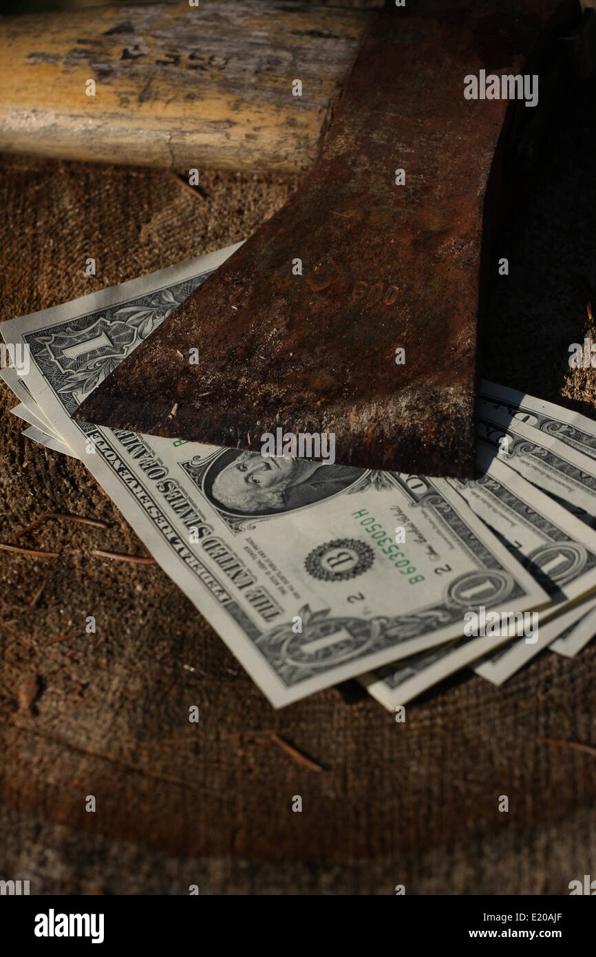 Dollar bills under sharp old axe Stock Photo