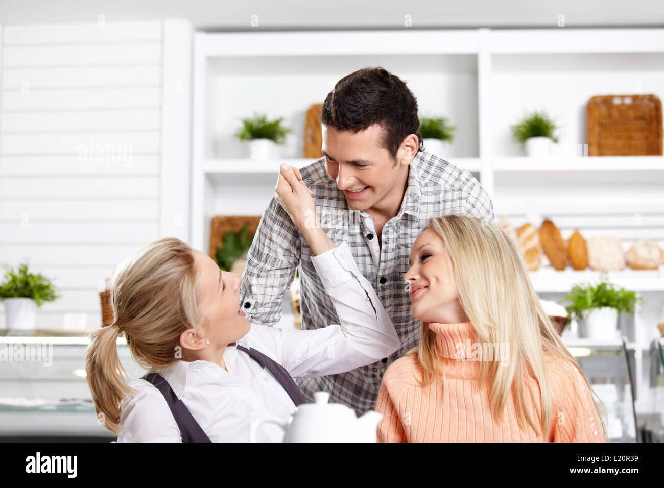Two girls and the guy have fun in cafe Stock Photo