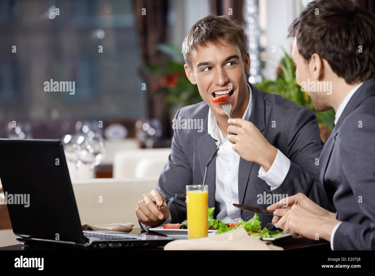 Two smiling business men eat at restaurant Stock Photo