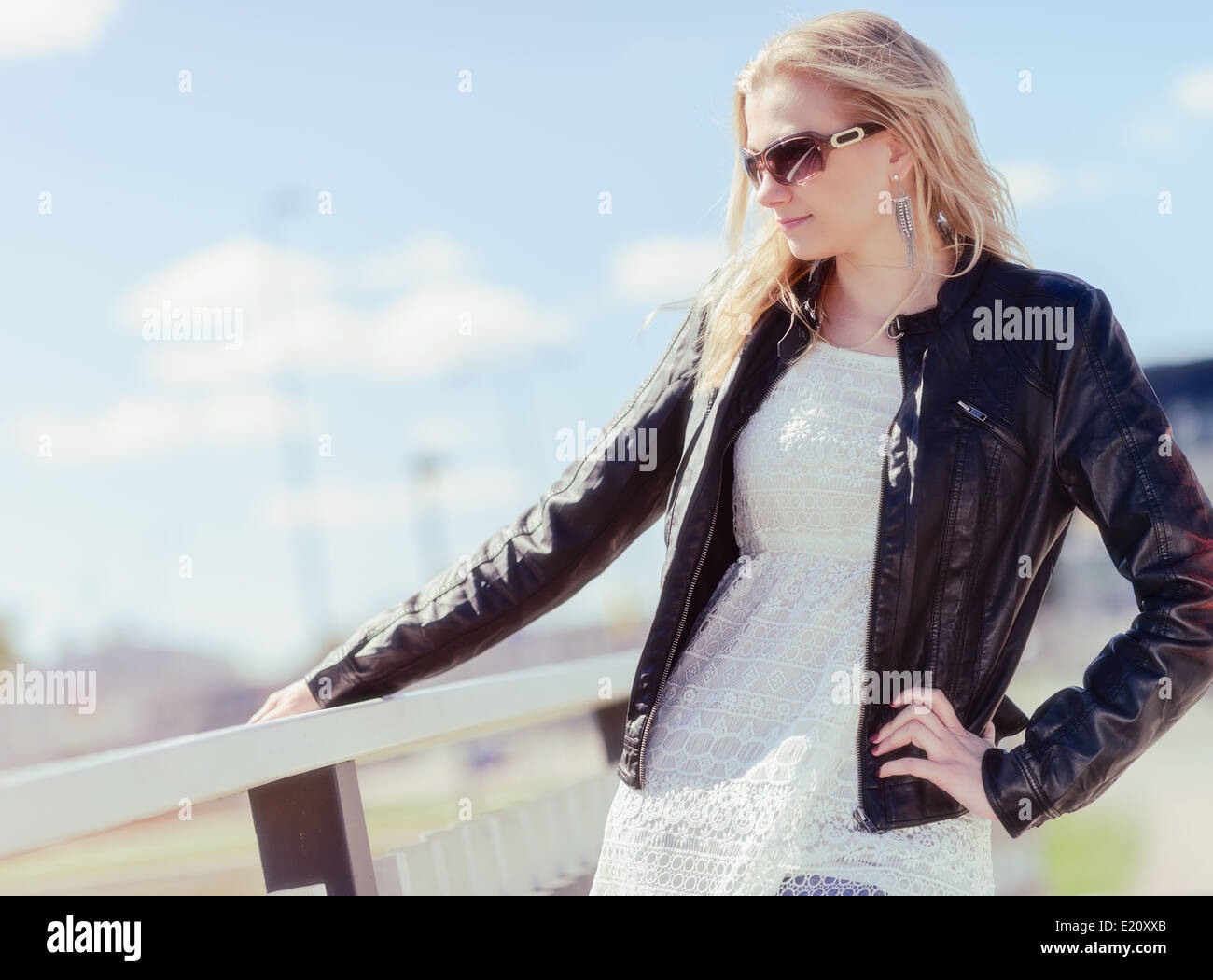 Fashionable beautiful young blond wearing a leather jacket, warm sunny day Stock Photo