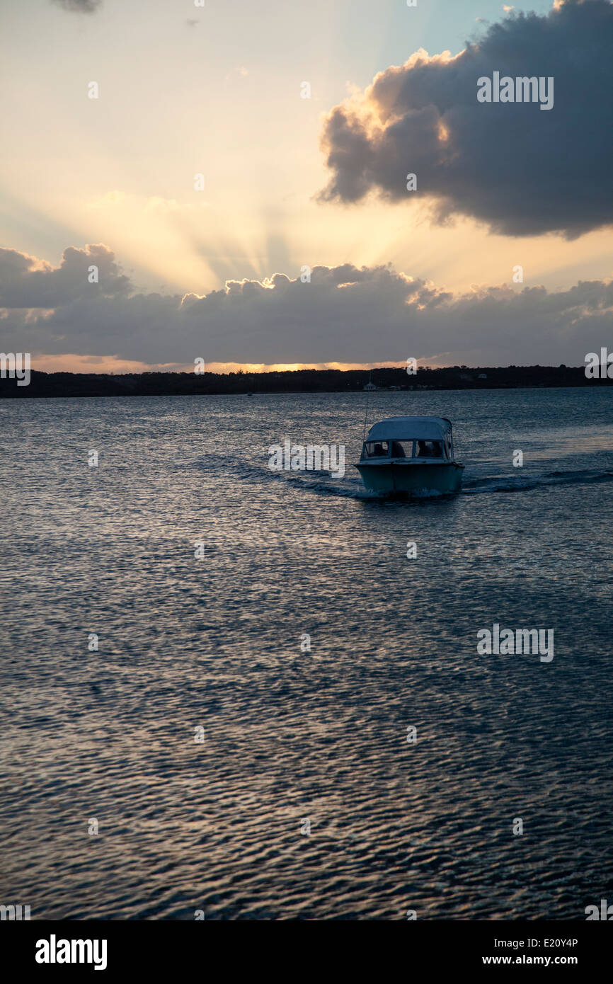 Boat coming to island back at sunset Stock Photo - Alamy