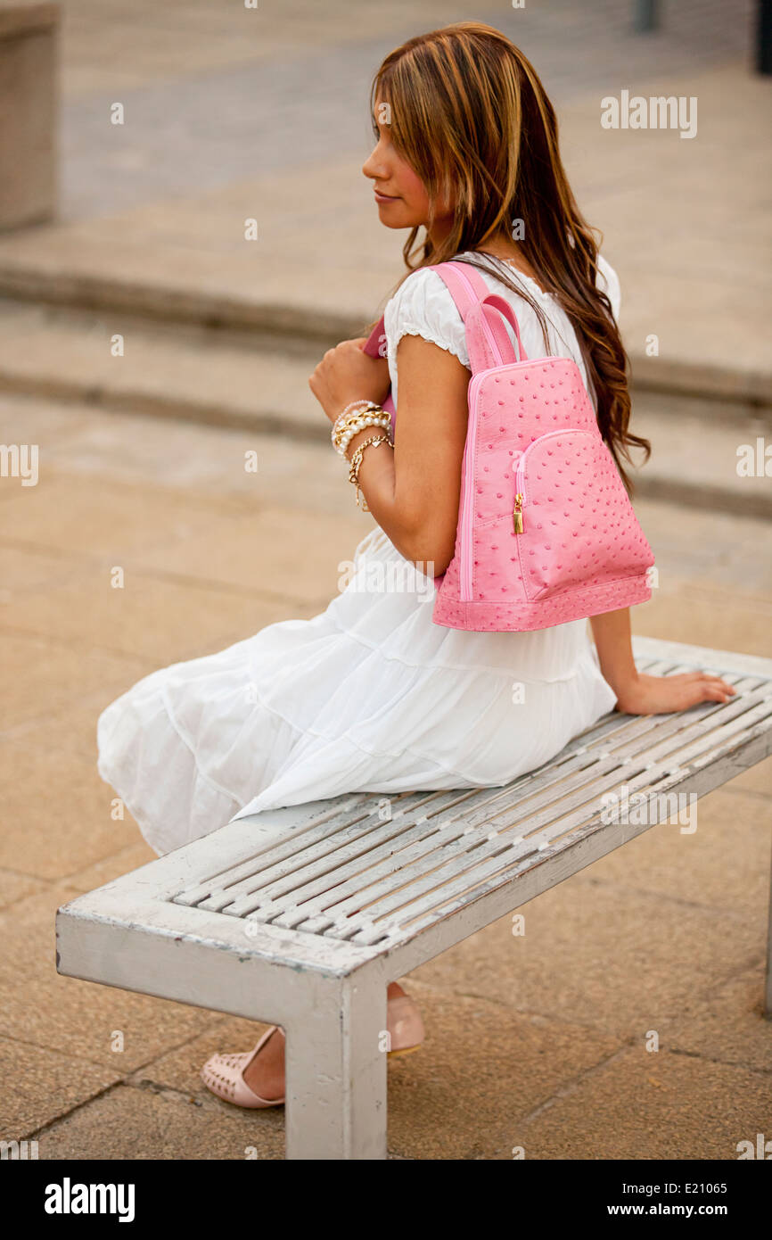 Feminine lady modeling a pink leather backpack wearing blue denim shirt and white skirt Stock Photo