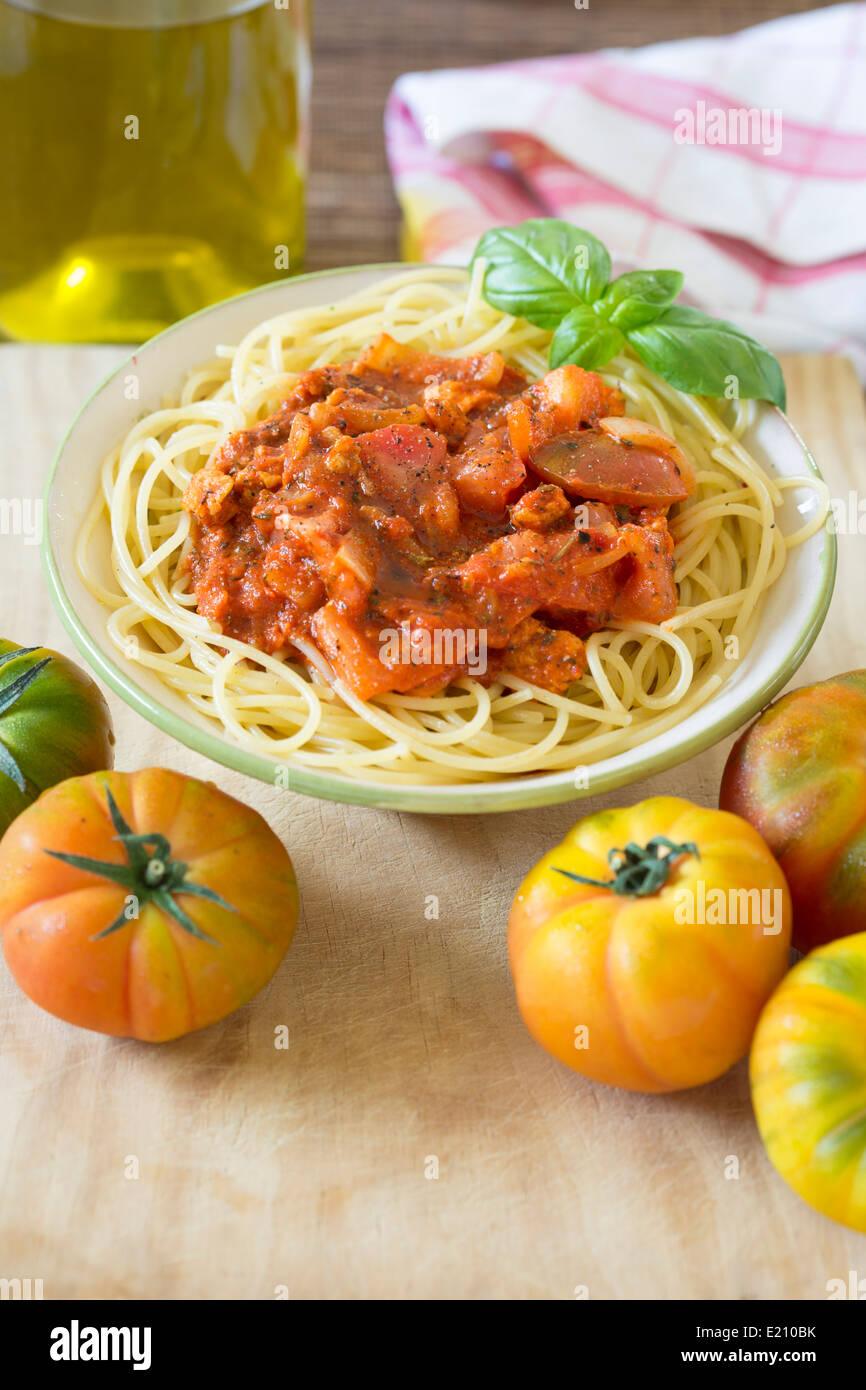 Bowl of spaghetti with vegetarian tomato bolognese sauce on wooden board and fresh Raf tomatoes. Stock Photo