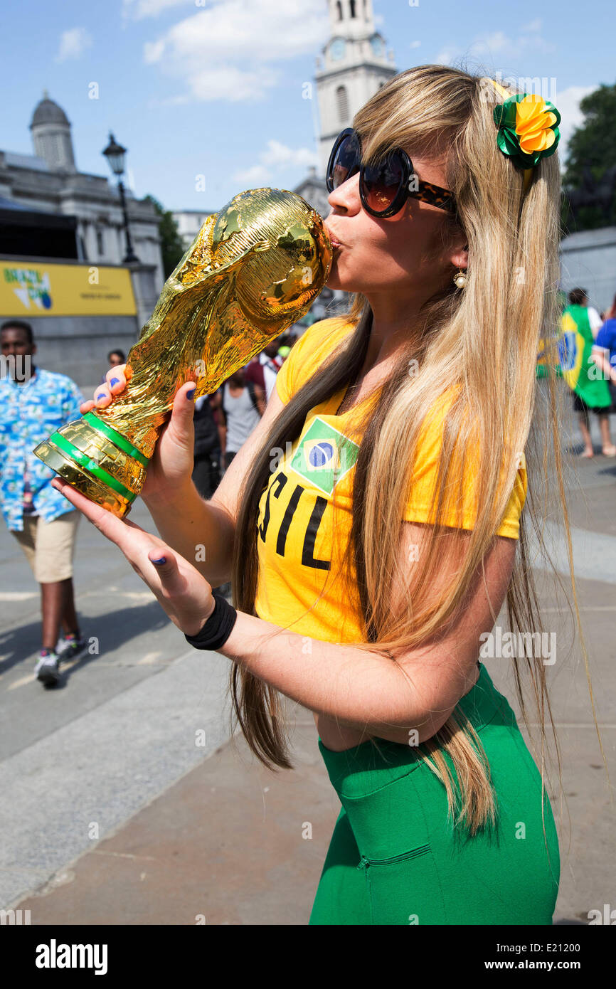 London, UK. Thursday 12th June 2014. Woman posing with a World Cup trophy. Brazilians gather for the Brazil Day celebrations in Trafalgar Sq. A gathering to celebrate the beginning of the Brazil 2014 FIFA World Cup. Revellers sing and dance and play football games and all in the yellow green and blue of the Brazilian flag. Credit:  Michael Kemp/Alamy Live News Stock Photo