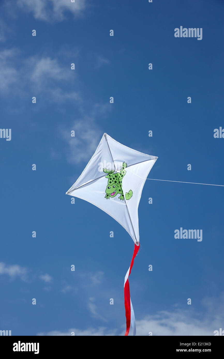 childs kite with frog design flying against blue sky Stock Photo