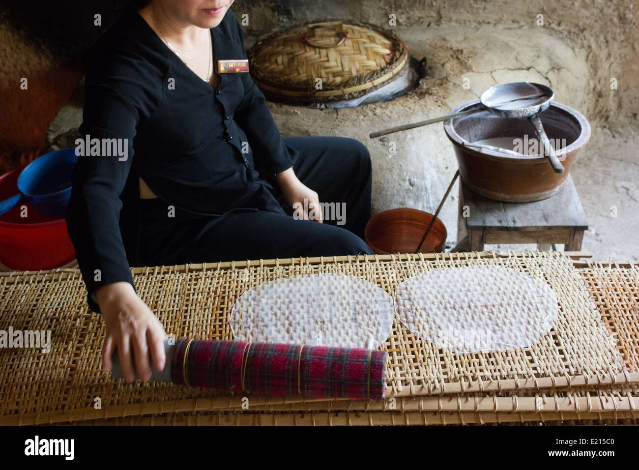 A lady making rice paper and leaving it to dry at the Cu Chi Tunnels in Ho Chi Minh City, Vietnam. Stock Photo