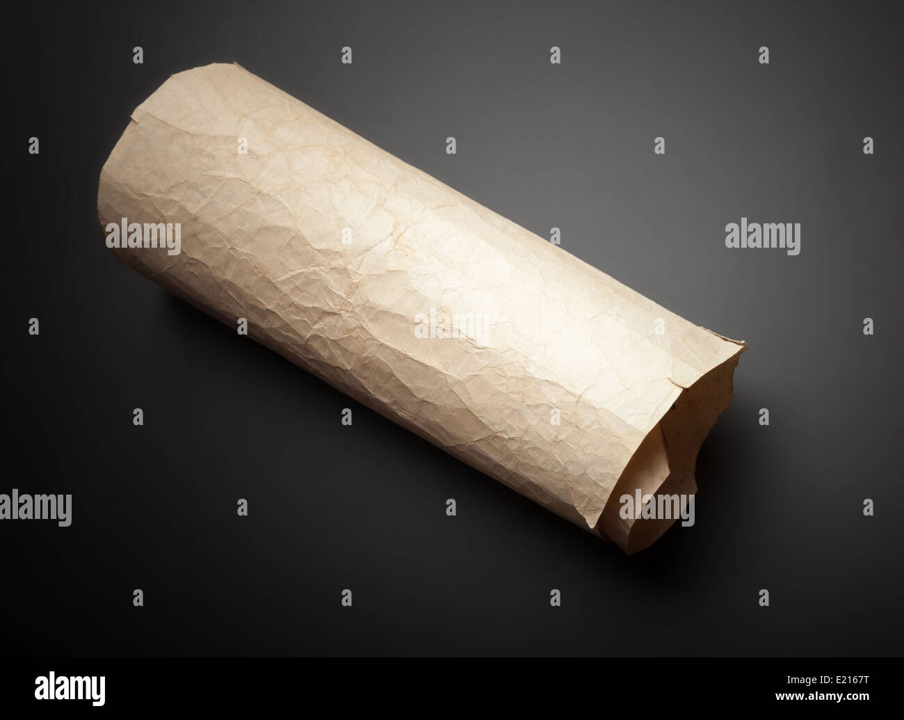 Old yellow crumpled paper roll on black table Stock Photo