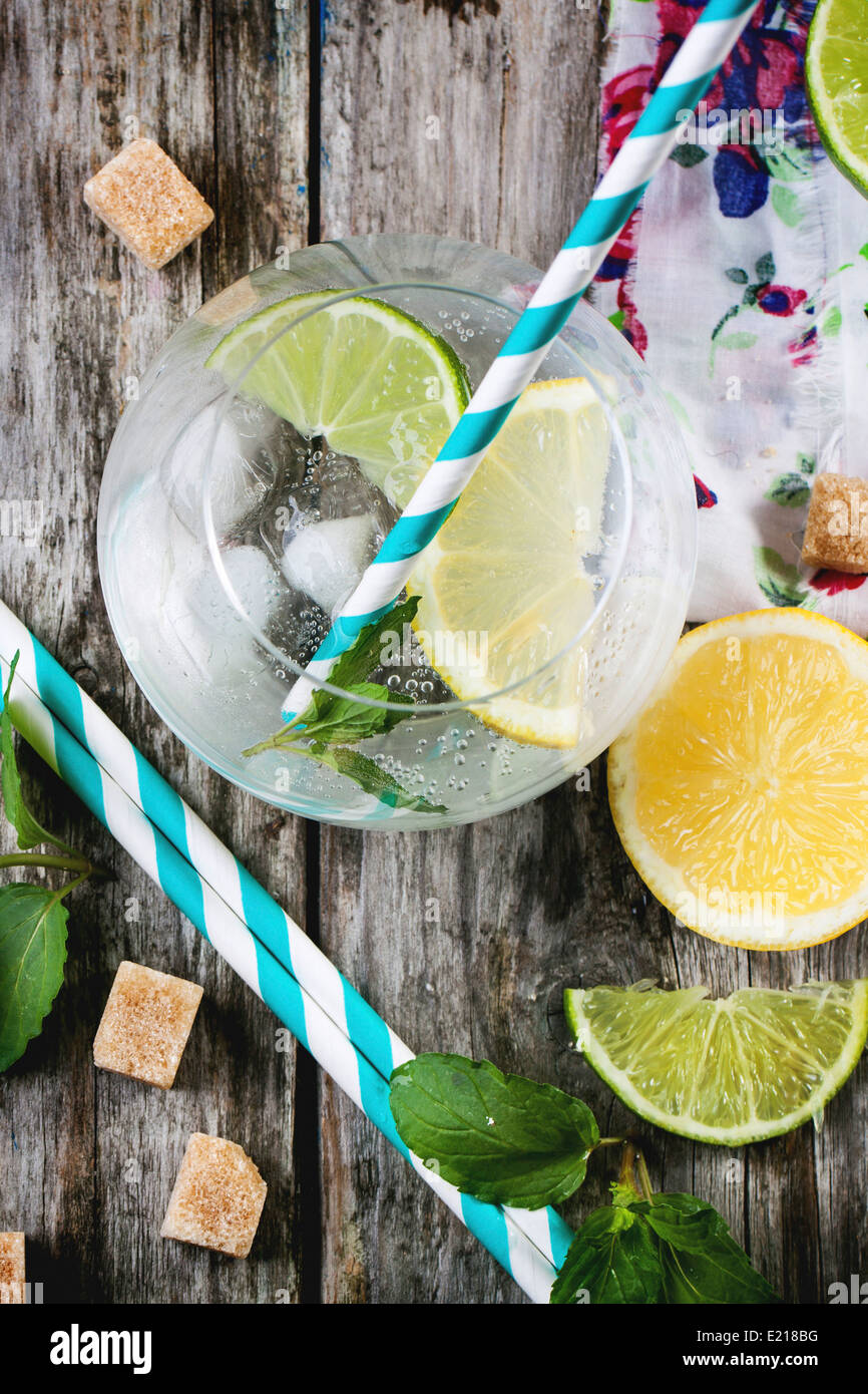 Fresh homemade lemonade with lemon, lime and mint in glasses with vintage cocktail tube over wooden table. Top view. Stock Photo