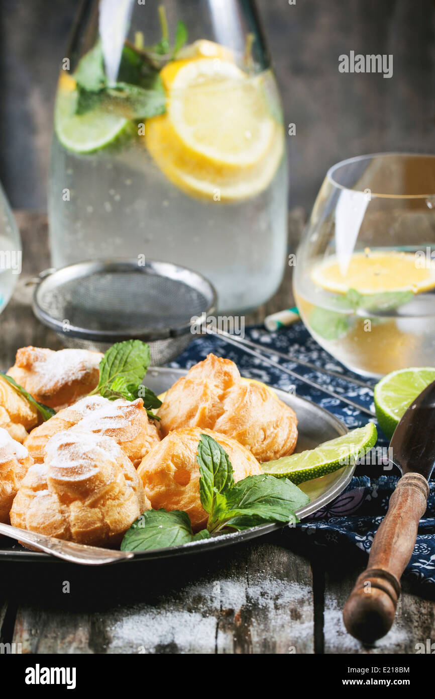 Vintage plate of homemade cakes profiteroles served with lemonade on old wooden table Stock Photo