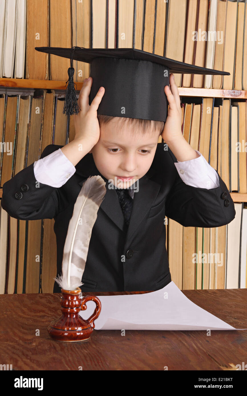 Child as a professor with quill and paper in library Stock Photo