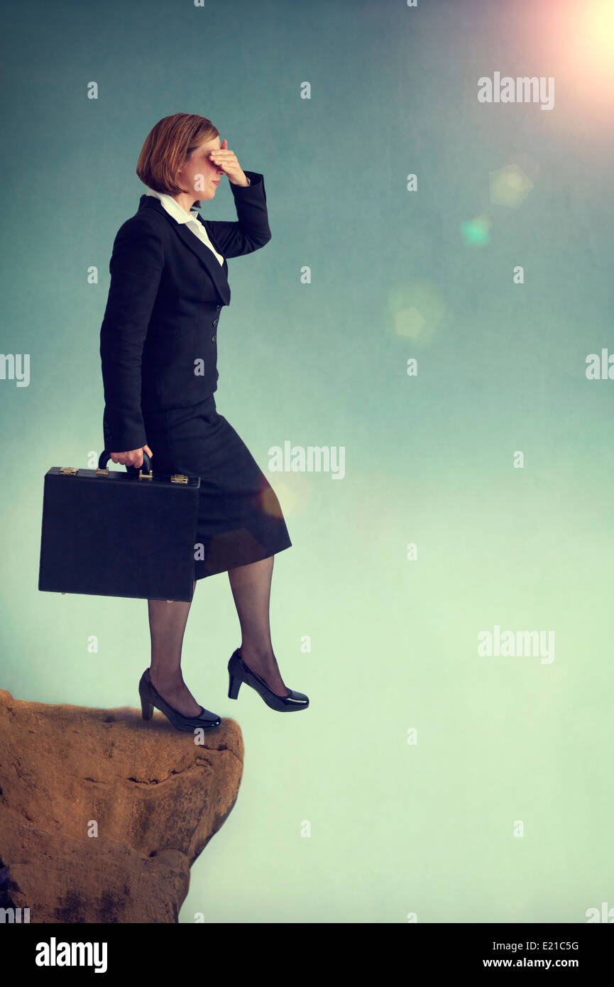 businesswoman stepping off a cliff or precipice without looking. Look before you leap concept Stock Photo