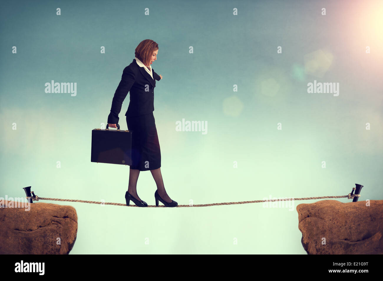 businesswoman balancing on a tightrope facing a challenge or risk or conquering adversity concept Stock Photo