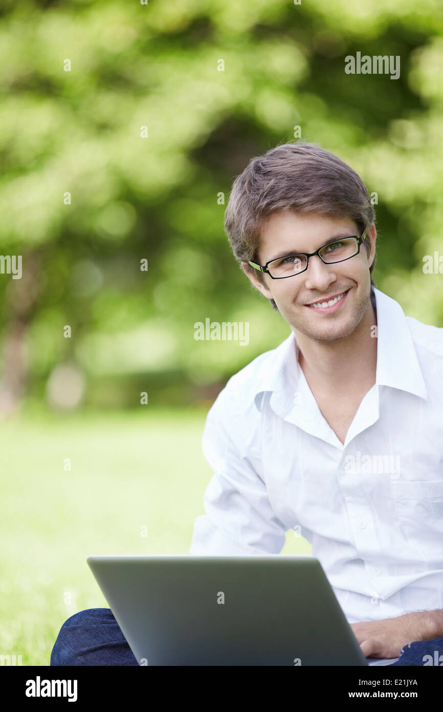 A smiling young man with laptop outdoor Stock Photo - Alamy