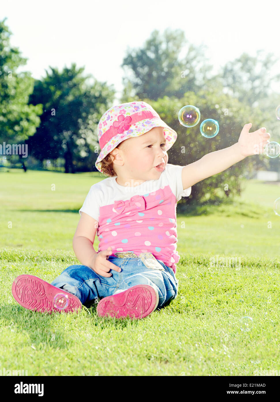Little girl catching the soap bubbles in a park Stock Photo - Alamy