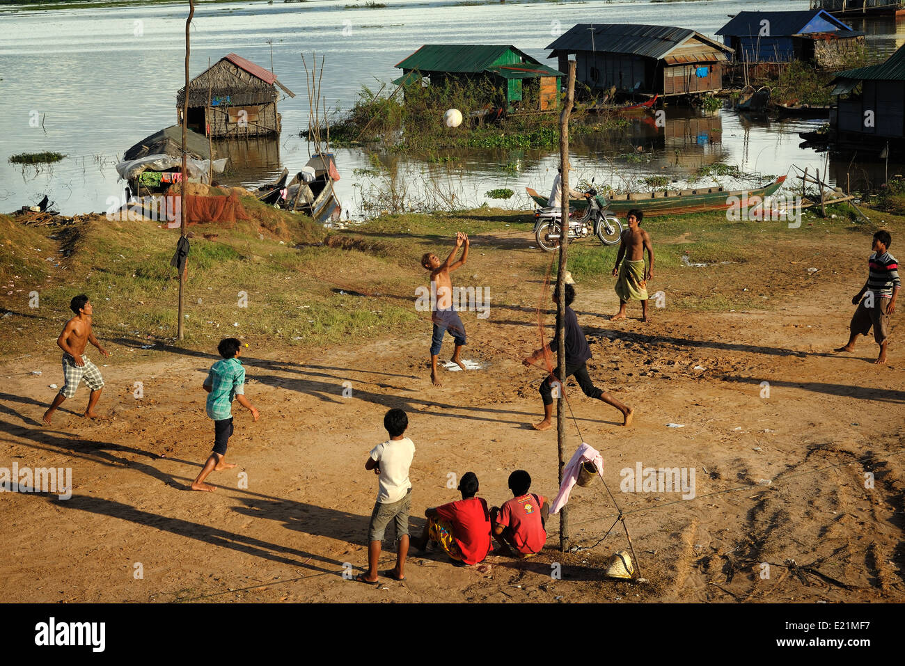 Boys are playing volleyball on a piece of dry land in the floating village of Chong Kneas, Tonle Sap Lake, Cambodia Stock Photo