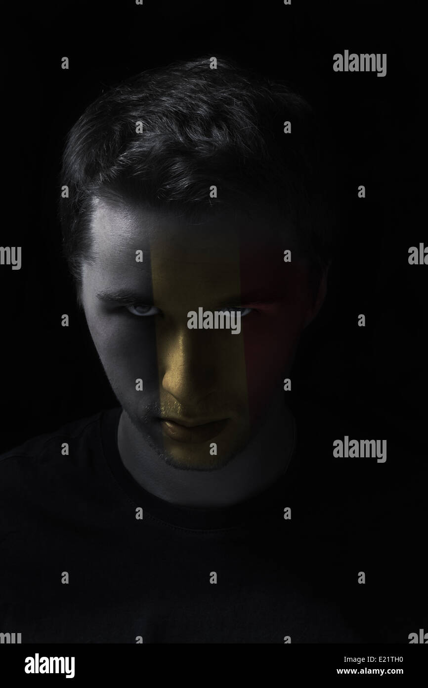 serios man face with painted flag colors of Belgium, black background Stock Photo