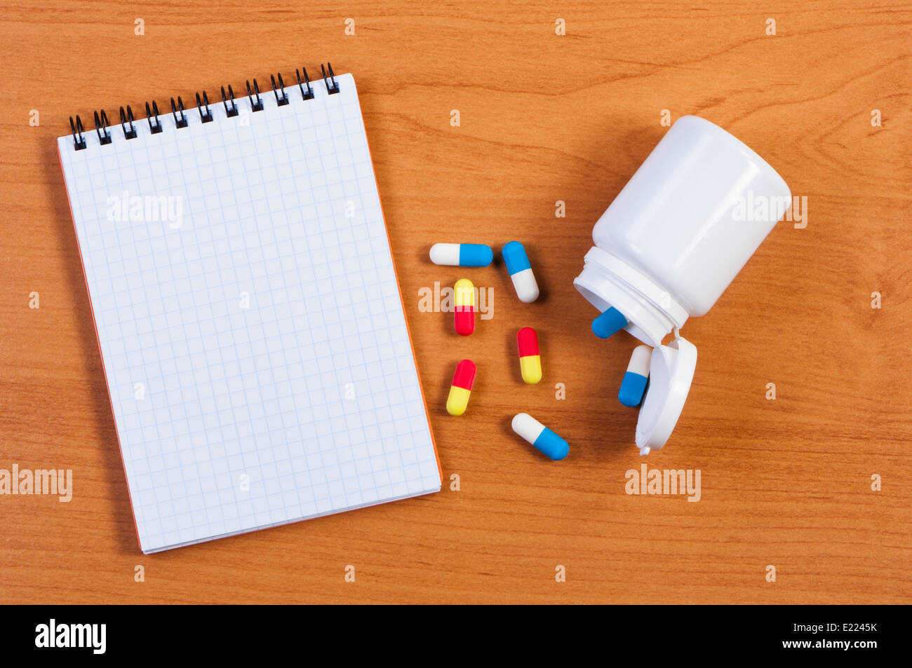 Notebpad and pills on table top view. Stock Photo