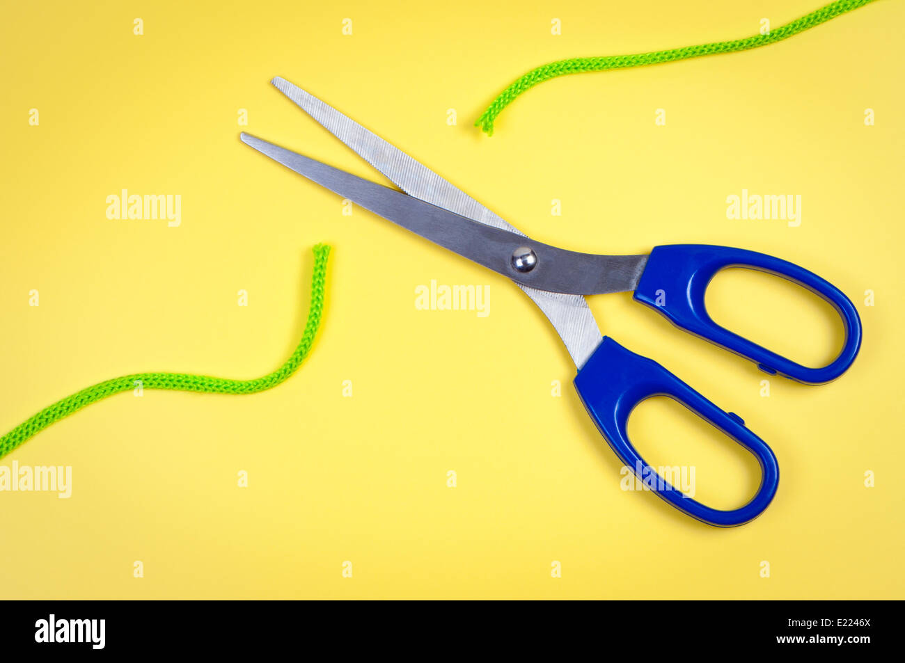 Scissors cut rope on a yellow background. Stock Photo