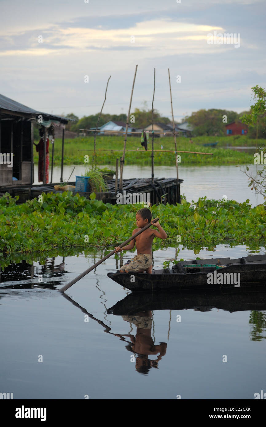 Boy rowing a boat within a floating village Stock Photo