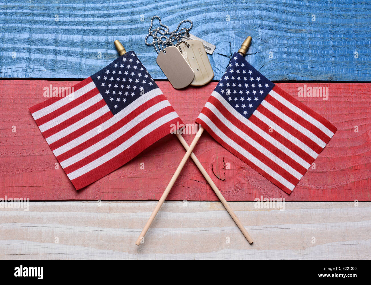 Two crossed American flags on a red, white and blue wood table with military dog tags. Great concept image for the 4th of July, Stock Photo