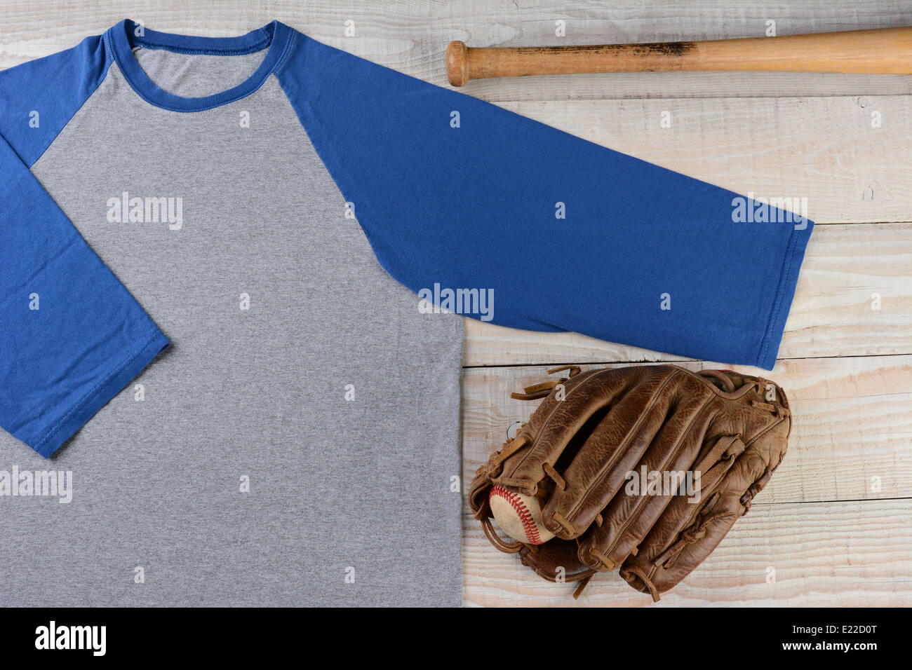 High angle shot of a Baseball jersey with a ball and glove and bat on wooden surface. Stock Photo