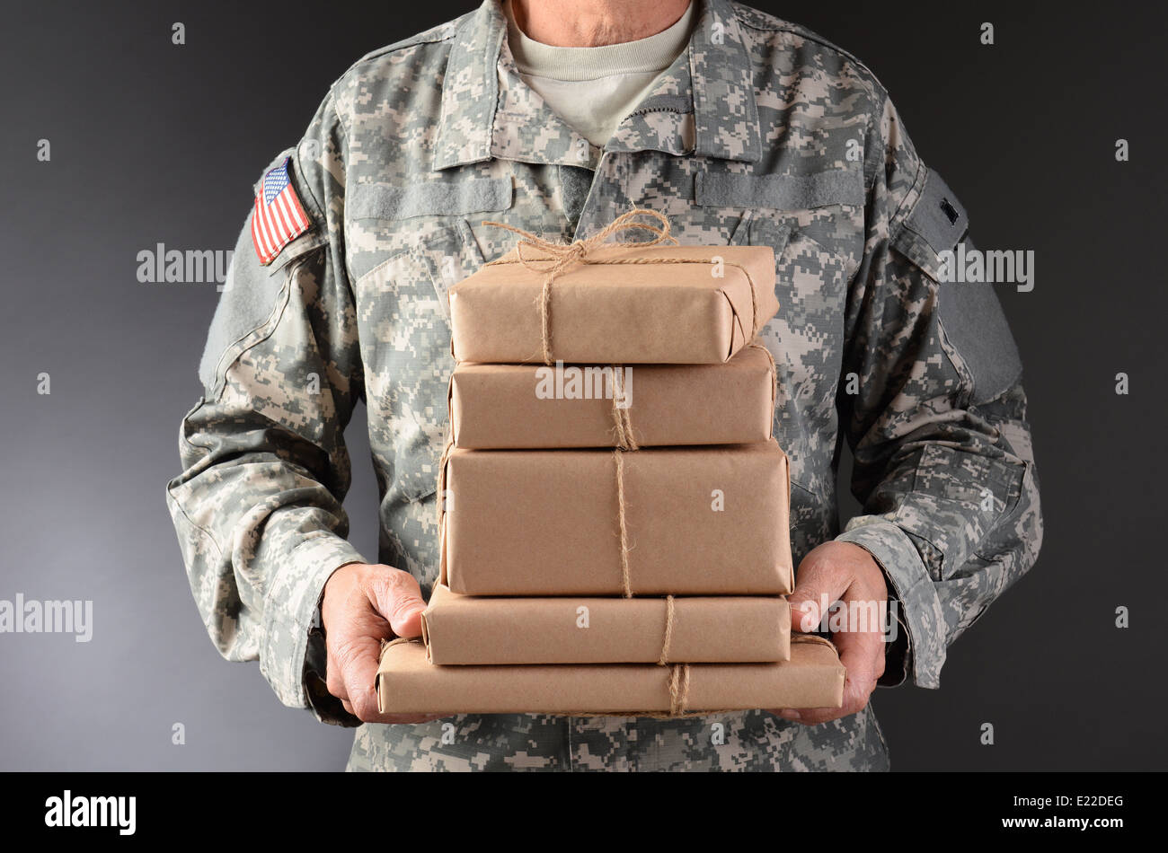 Closeup of a soldier wearing camouflage fatigues holding a stack of packages for mail call. Stock Photo