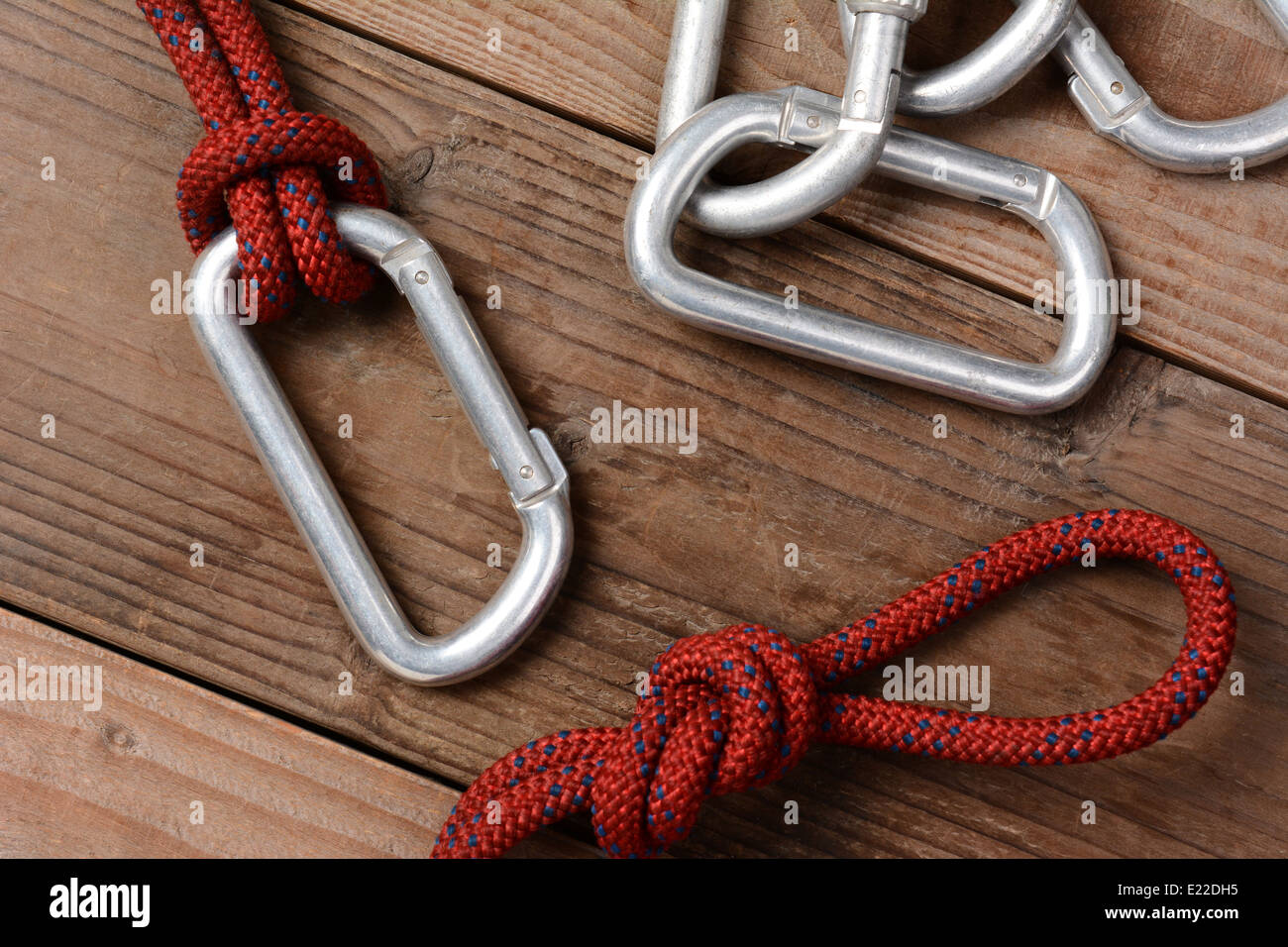 Closeup of a climbing rope and carabiners on a rustic wooden cabin floor. Horizontal format. Stock Photo