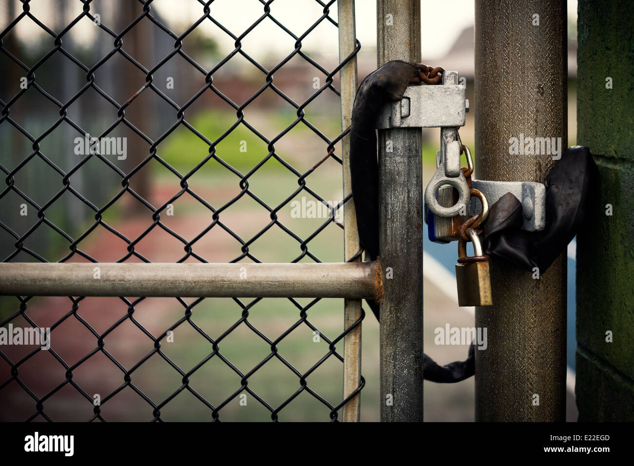 Closeup of a locked padlock securing a metal chain-link gate. Stock Photo