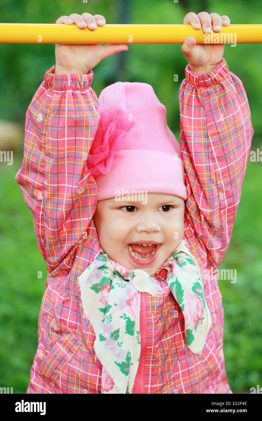 Funny smiling Caucasian baby girl in pink, outdoor portrait Stock Photo