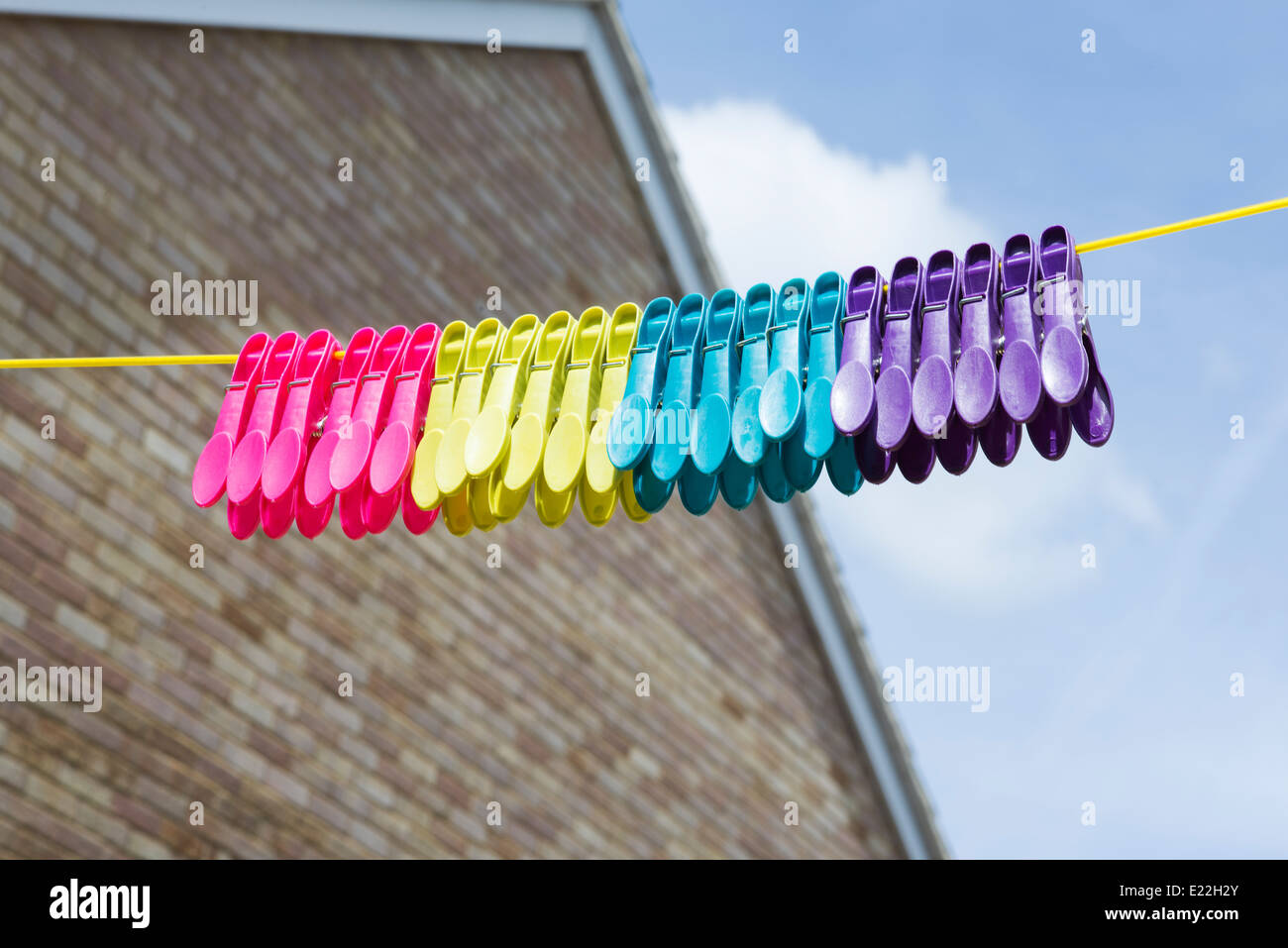 Multi coloured plastic pegs hanging on a washing line Stock Photo