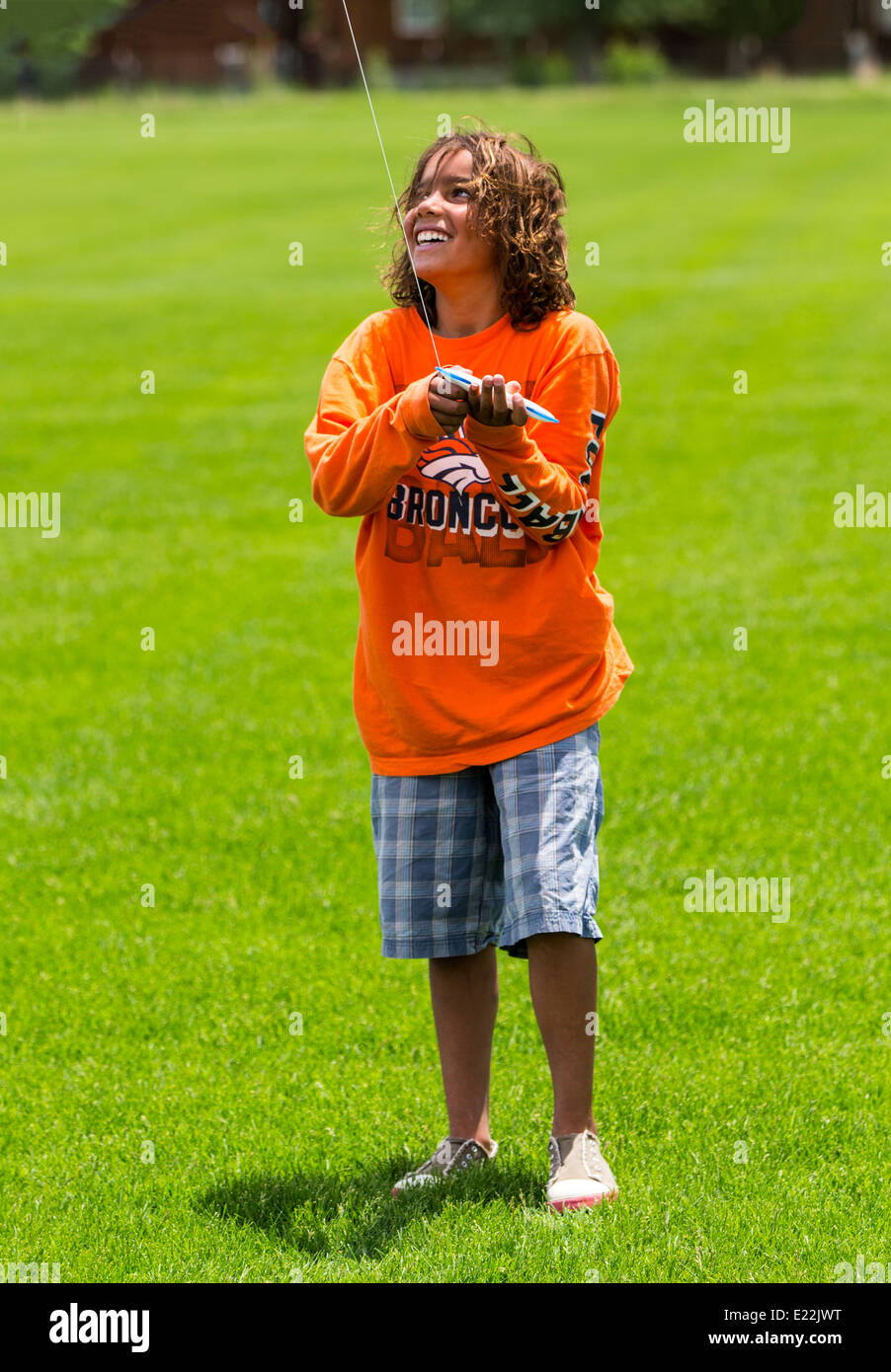 Young boy flying a kite on a grassy field Stock Photo