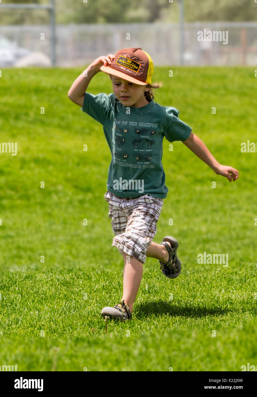 Young boy running on a grassy park field Stock Photo