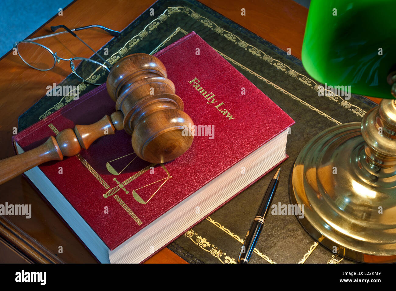 LAW COURT CHAMBERS JUDGE SENTENCING DELIBERATIONS wooden gavel on 'Family Law' book with scales of justice emblem lit by desk lamp on traditional desk Stock Photo