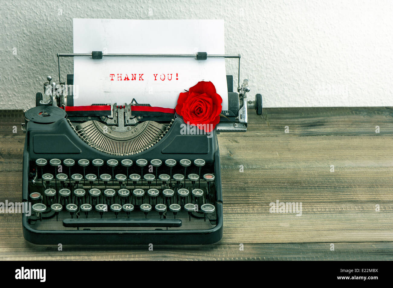 vintage typewriter with white paper page and red rose flower. sample text Thank You! Stock Photo
