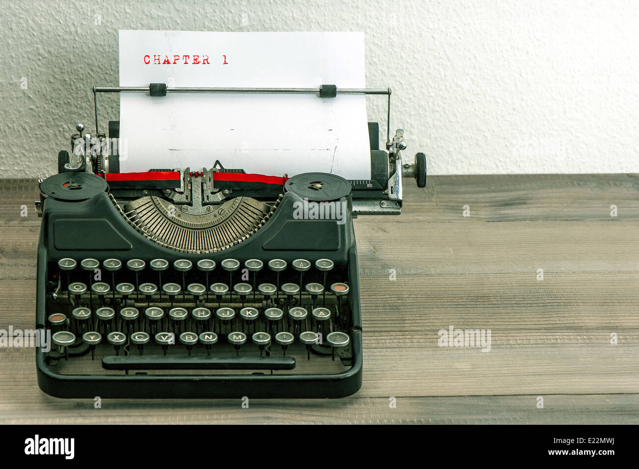 typewriter with white paper page on wooden table. sample text Chapter 1 Stock Photo