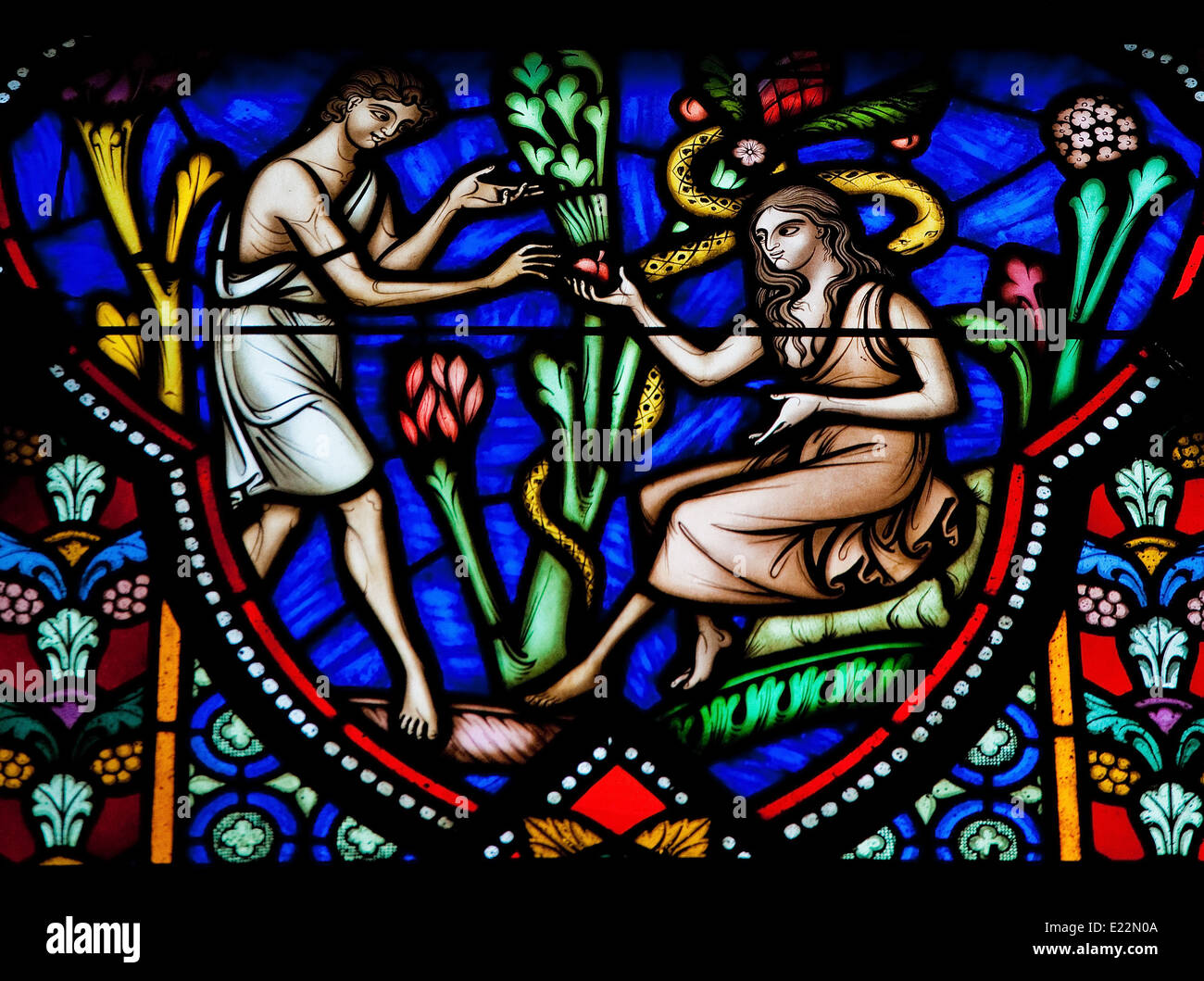 Adam and Eve eating the Forbidden Fruit in the Garden of Eden on a stained glass window in the cathedral of Brussels. Stock Photo