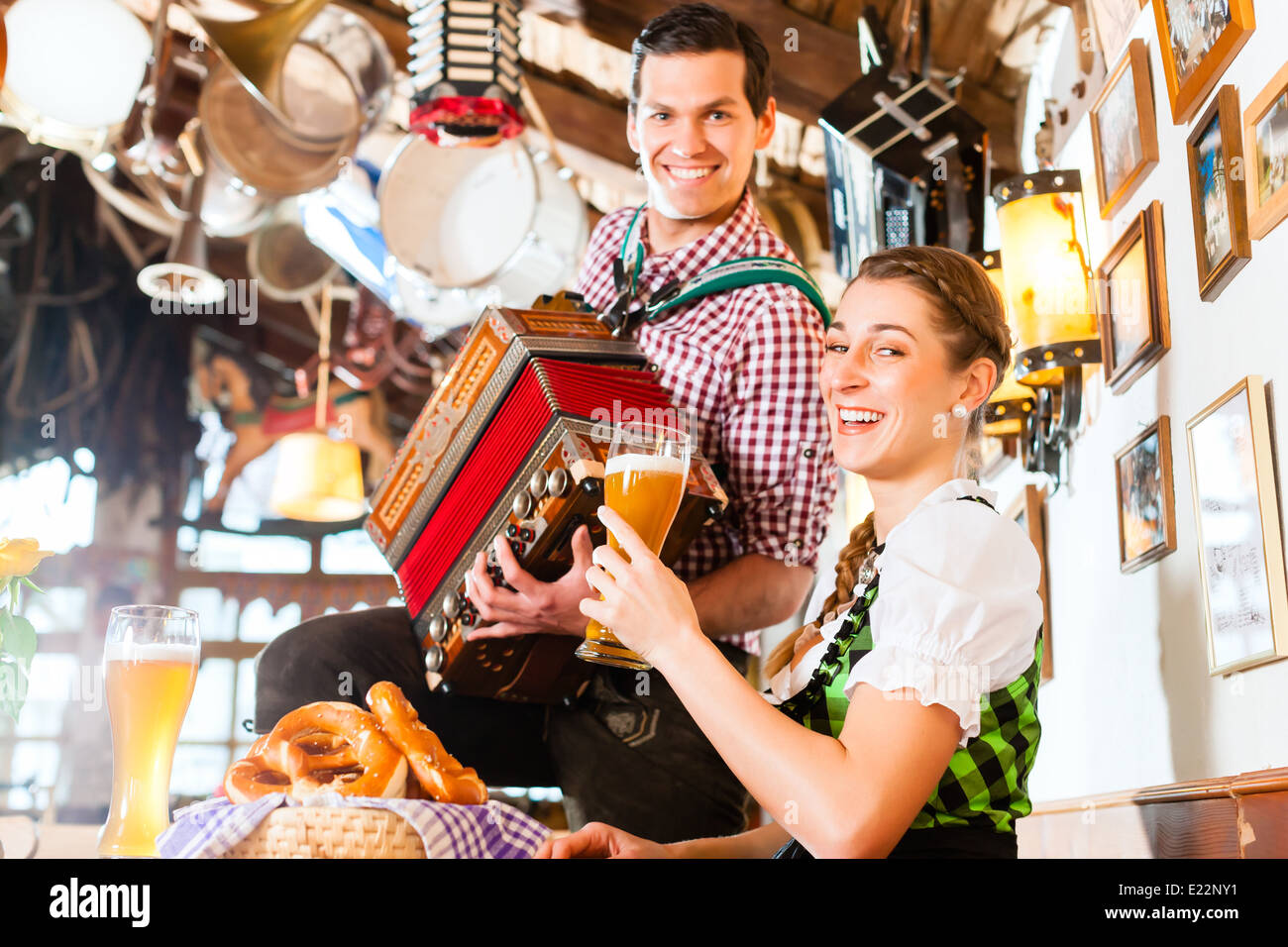 Bavarian man playing folk music for woman wearing dirndl Stock Photo