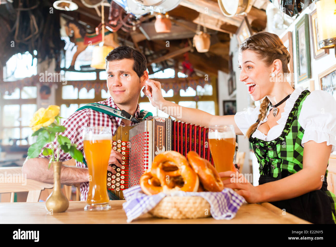 Bavarian man playing folk music for woman wearing dirndl Stock Photo