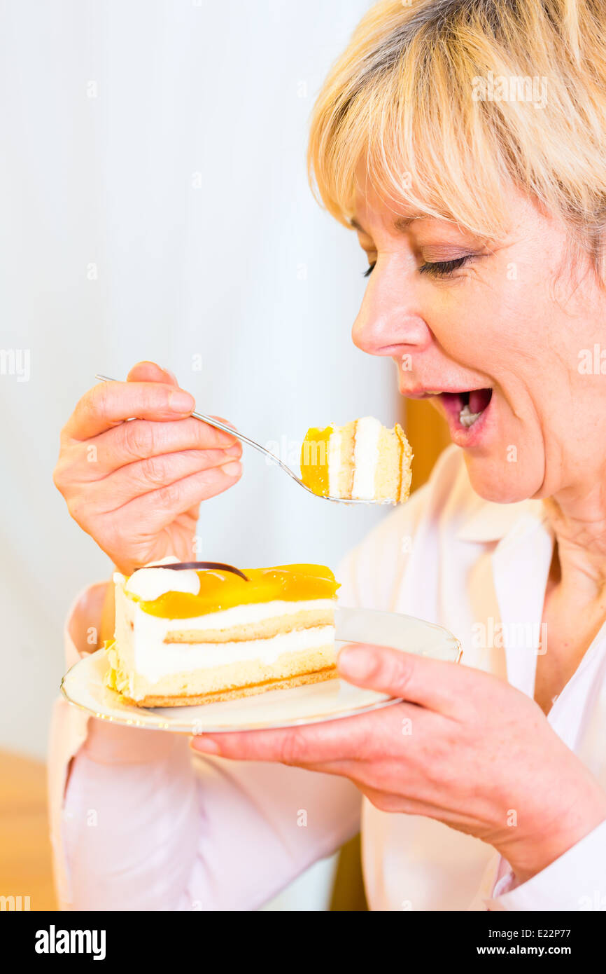 Old woman eating cake in the afternoon Stock Photo. 