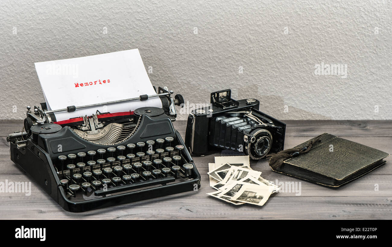retro typewriter and vintage photo camera on wooden table. White paper page with sample text Memories Stock Photo