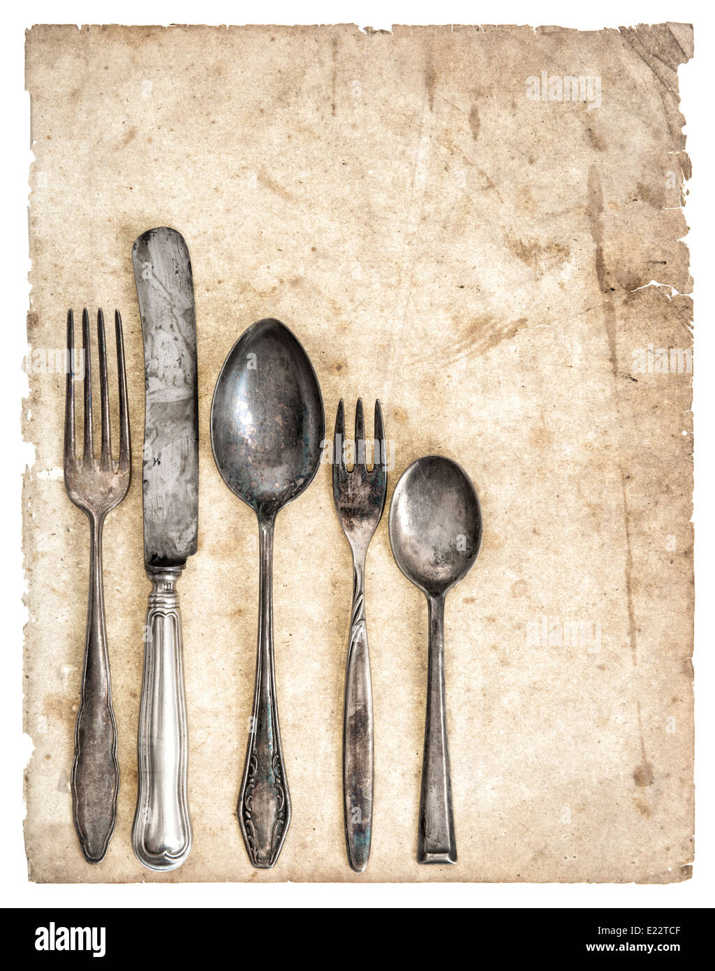 Antique cutlery and old cook book page isolated on white background. Retro kitchen utensils knife, fork and spoons Stock Photo