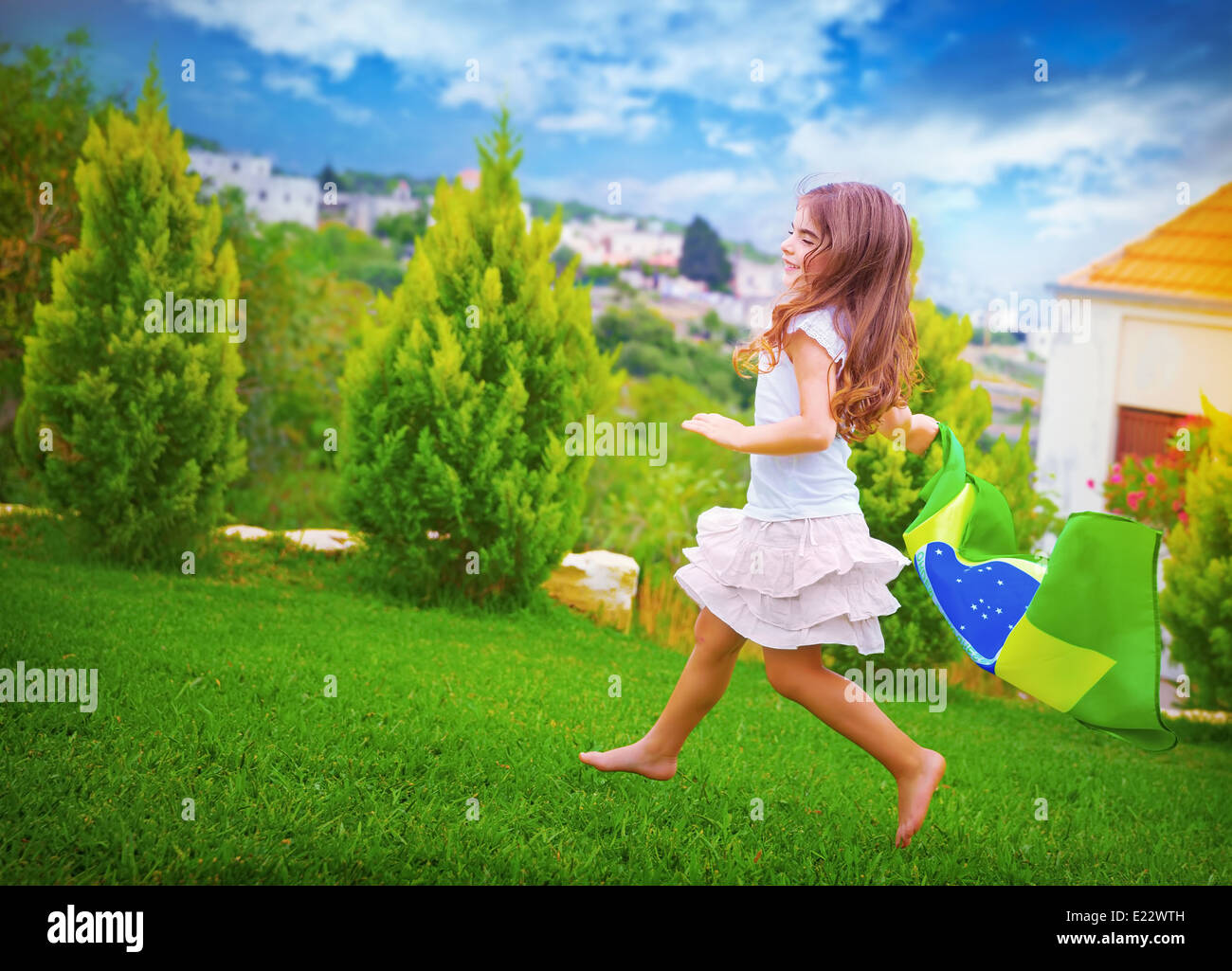 Happy football fan, cute little girl running on backyard with national